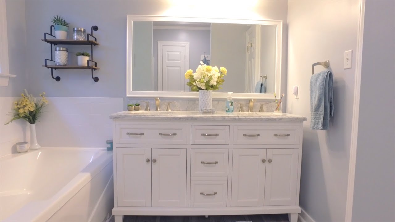 Elegant Bathroom Remodeling Electrical featuring a white double vanity, illuminated mirror, modern lighting, and a spacious bathtub for a bright, stylish space.
