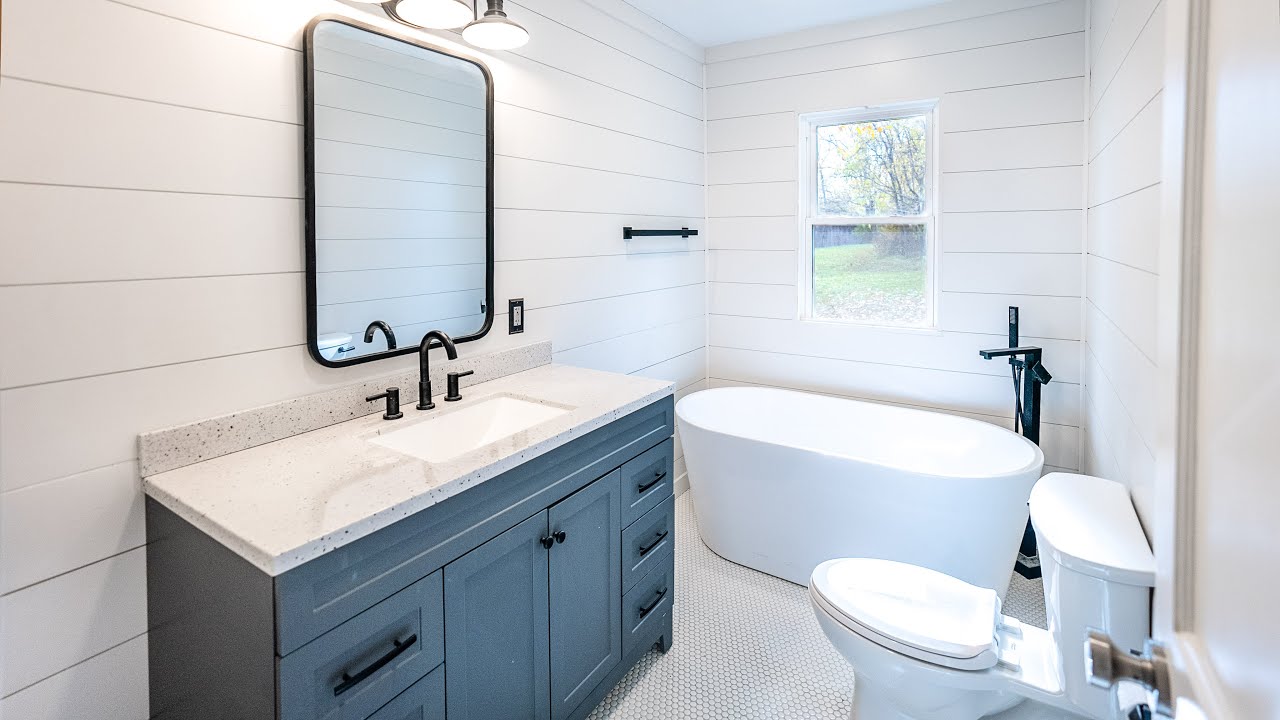 Modern Bathroom Remodeling Electrical featuring a gray vanity, quartz countertop, freestanding bathtub, black fixtures, and bright shiplap walls.