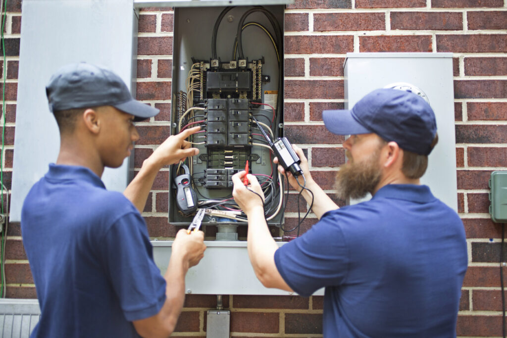 Electricians performing Home Electrical Maintenance and Repair, inspecting a residential electrical panel and wiring for safe, reliable power.