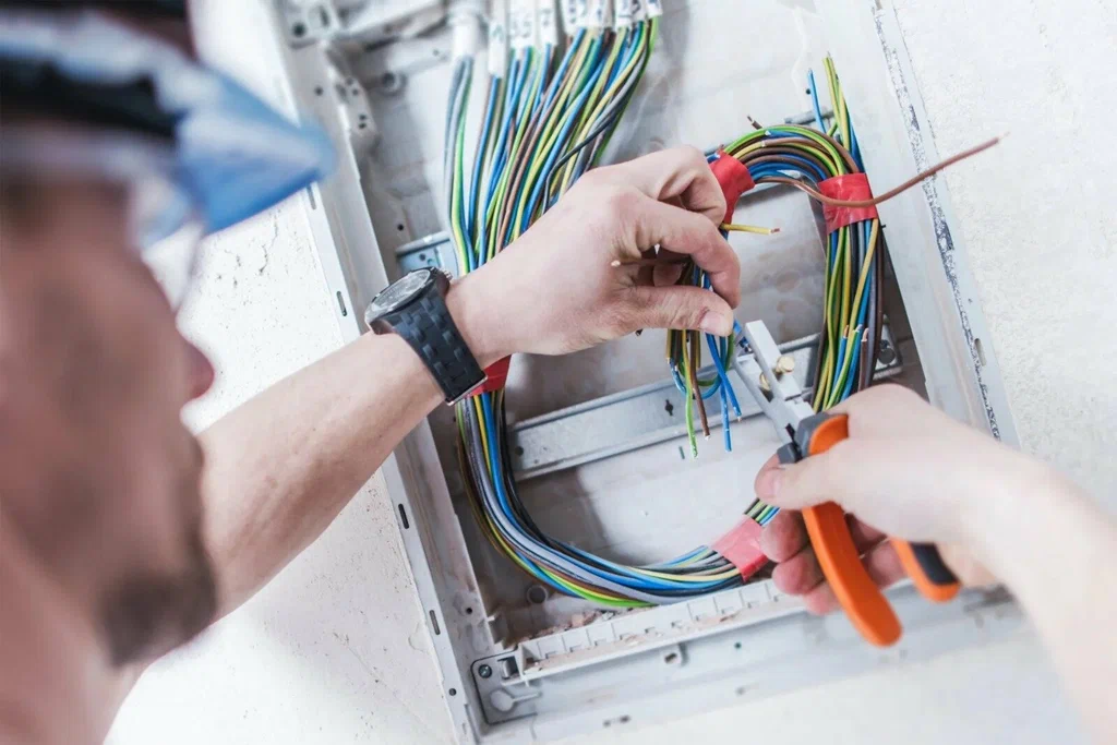 Commercial Electrical Wiring Expert Connecting Control Panel Cables A commercial electrical wiring expert carefully connects and organizes multicolored electrical cables inside a control panel to ensure safe, efficient, and reliable wiring for commercial buildings.